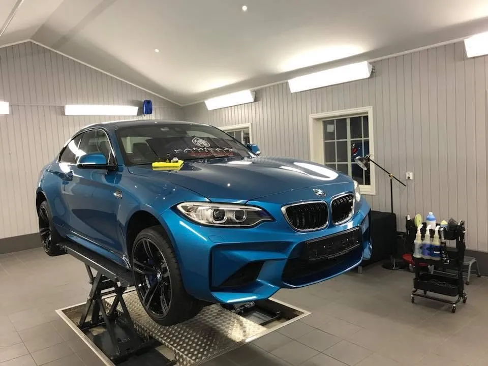 Blå BMW M2 på løftebordet under coating